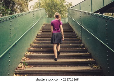 A Young Woman Is Walking Up Stairs Outside In A Park