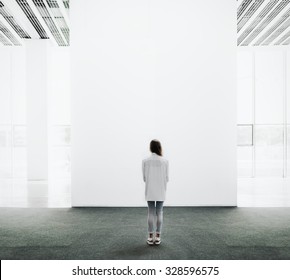 Young woman walking through a gallery and looking at the canvas