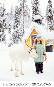 Mujer joven caminando con reno blanco en bosque invernal en Laponia, Finlandia