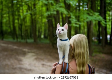 Young Woman Walking In The Woods With A Young White Cat In The Back Pack