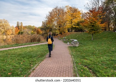 A young woman walks along a footpath in a park in the fall. - Powered by Shutterstock