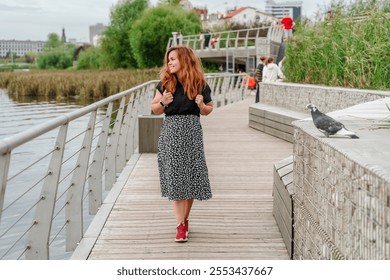 A young woman walks with a backpack in the park on the embankment near the city lake. - Powered by Shutterstock