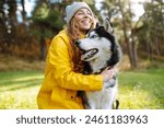 A young woman walks with her dog in the autumn forest. Husky dog.  Pet owner enjoys walking her dog outdoors.