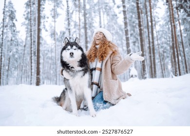 A young woman walks with her dog in the winter forest. Husky dog. Pet owner enjoys walking her dog outdoors. Friendship concept, pets. - Powered by Shutterstock