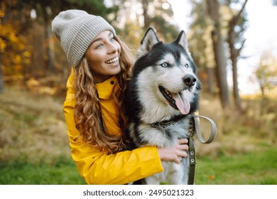 Young woman walks with her husky on the lawn in the park. Playing together. Concept of friendship, pet, vacation. - Powered by Shutterstock