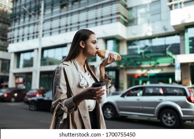 Young Woman Walks Out Of The Office And Eats A Sandwich On The Go, Kisses A Loaf, In A Hurry