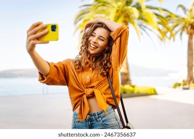 Young woman walks the streets and takes selfie using smartphone camera. Beautiful young photographer takes pictures for her travel blog. - Powered by Shutterstock