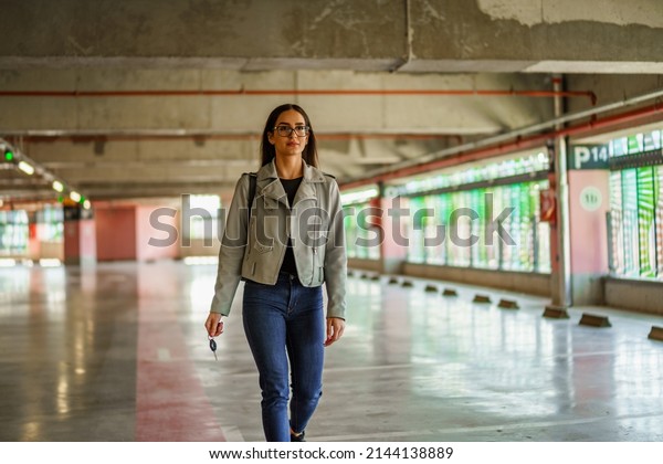 A young woman walks through the parking lot as she\
walks to her car.