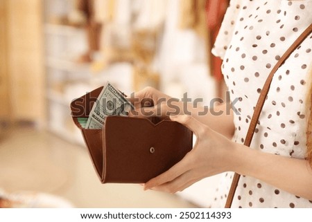 Young woman with wallet and money in boutique, closeup