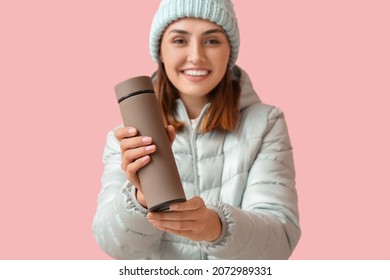 Young woman in warm clothes and with thermos on color background