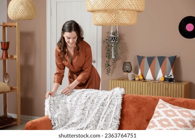 Young woman with warm plaid on sofa at home - Powered by Shutterstock