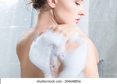 Young Woman Washing Body In A Shower. Rear View