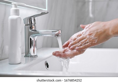 Young Woman Washing Cleansing Soapy Hands In Bathroom To Prevent Coronavirus Infection, Cleaning Skin Care In Foam,rubbing Hands Rinsing With Running Water. Covid 19 Protection Concept. Close Up View.