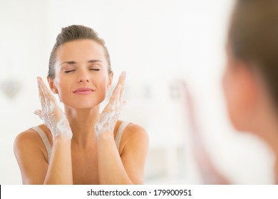 Young Woman Washing Face In Bathroom