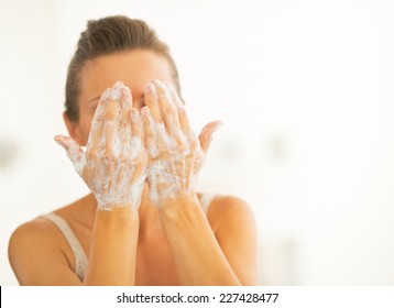 Young woman washing face in bathroom - Shutterstock ID 227428477