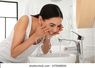 Young Woman Washing Face With Cosmetic Product In Bathroom