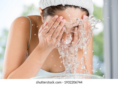 Young woman washing face in room.