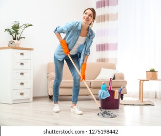 Young woman washing floor with mop in living room. Cleaning service - Shutterstock ID 1275198442