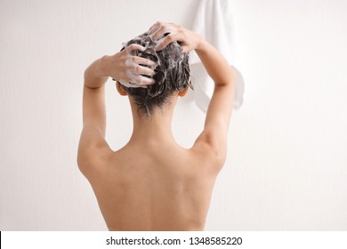 Young woman washing hair in bathroom