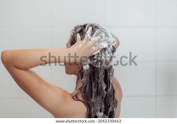 Young woman washing hair in shower. Asian woman\
washing her black hair.