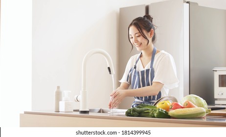 Young woman washing hands in the kitchen - Powered by Shutterstock