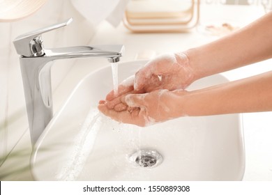 Young woman washing hands with soap over sink in bathroom, closeup - Shutterstock ID 1550889308