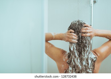 Молодая женщина стиральная головка с шампунь. вид сзади