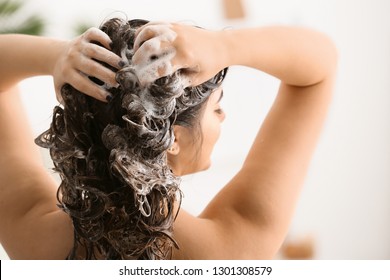 Young woman washing her beautiful hair in bathroom