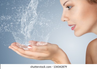 Young woman washing her face and hands with clean water in the morning