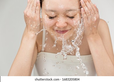 Young woman is washing her face.