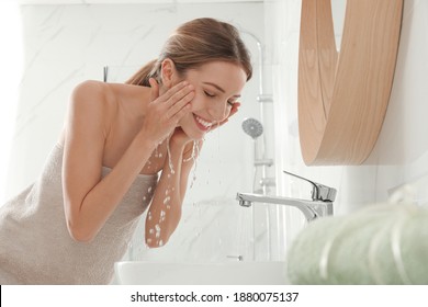 Young Woman Washing Her Face With Water In Bathroom