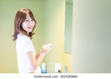 Junge Frau, die sich das Gesicht am Waschbecken wäscht