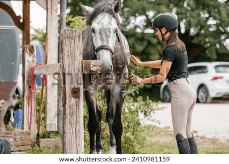 Young woman washing her horse on a farm after ride in summer