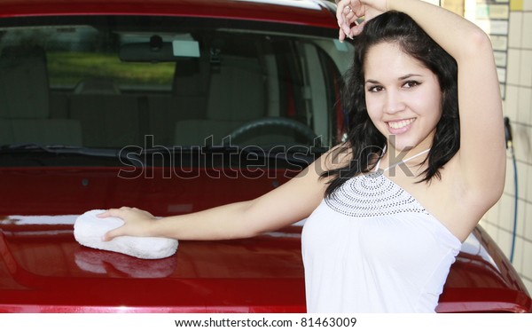 young woman washing red\
car with sponge