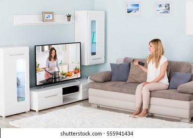 Young Woman Watching Cooking Show On Television At Home