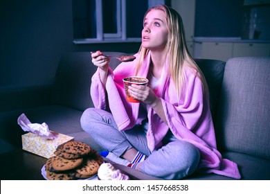 Young Woman Watching Movie At Night. Eating Ice Cream Or Chocolate With Spoon. Cookies On Table. Streaming Show On Tv.