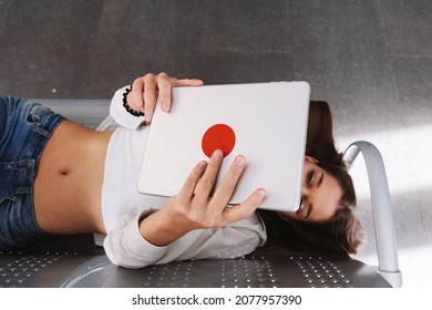 Young Woman Watching Tablet Lying On The Seats In The Waiting Room - Free Wifi Zone Of The Airport Or Station