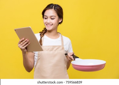 Young woman watching tablet PC while cooking.