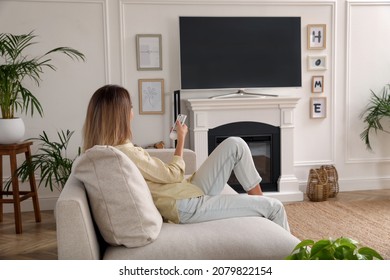 Young Woman Watching Television At Home. Living Room Interior With TV On Fireplace