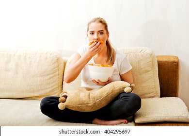 Young Woman Watching TV And Eating Chips