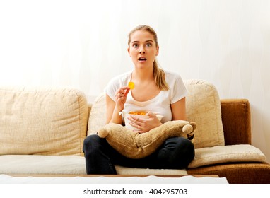 Young Woman Watching TV And Eating Chips