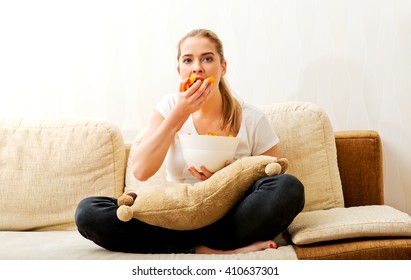 Young Woman Watching TV And Eating Chips