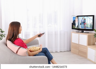 Young Woman Watching TV On Sofa At Home