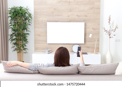 Young Woman Watching TV In The Room. White Empty Screen For Design