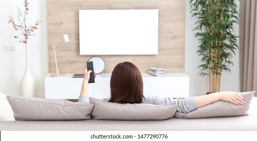 Young Woman Watching TV In The Room. White Empty Screen For Design