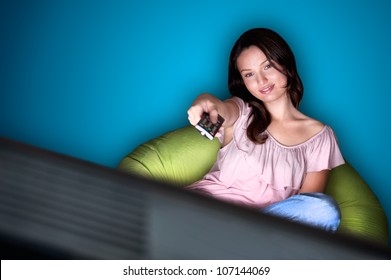 Young Woman Watching TV Sitting On The Beanbag At Home