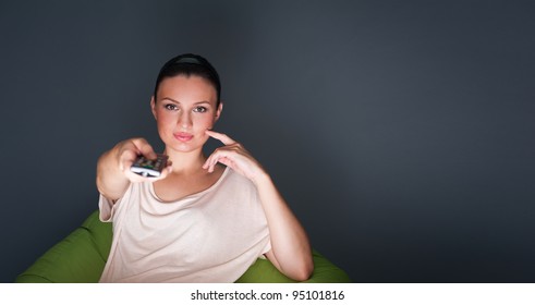 Young Woman Watching TV Sitting On The Beanbag At Home