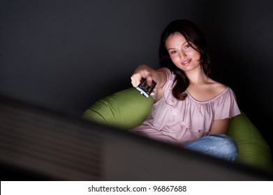 Young Woman Watching TV Sitting On The Beanbag At Home