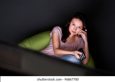 Young Woman Watching TV Sitting On The Beanbag At Home