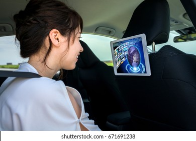 young woman watching a video at the rear seat of vehicle. automotive infotainment concept.
